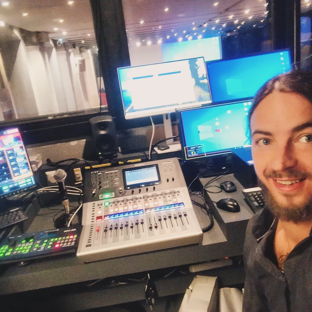 Andreas beside an audio mixing desk, screens and a microphone